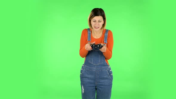 Girl Playing a Video Game Using a Wireless Controller with Joy and Loses. Green Screen