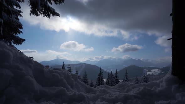 Moving clouds in the blue sky, sun behind the clouds, winter and a lot of snow