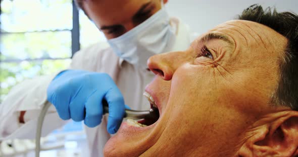 Dentist examining a male patient with tools