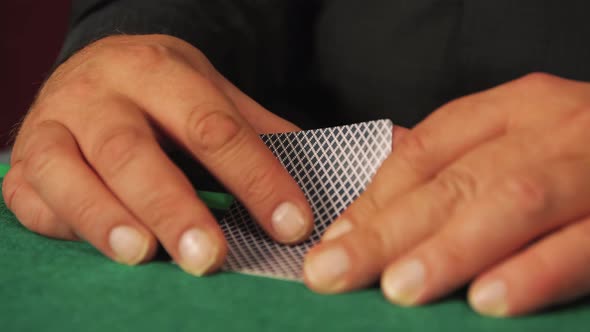 A Risky Poker Player in Closeup is Slowly Looking at His Cards
