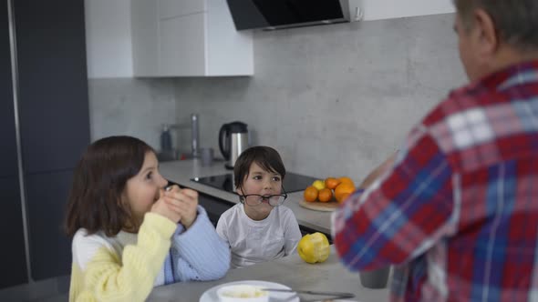 Two Small Children are Together with Grandfather