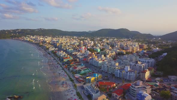 Aerial establishing shot of Bombas beach, a coastal city in Brazil at golden hour. Dolly in