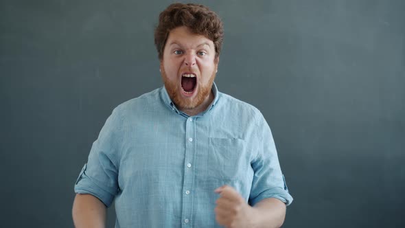 Slow Motion of Excited Person Expressing Positive Emotions and Screaming Looking at Camera on Gray