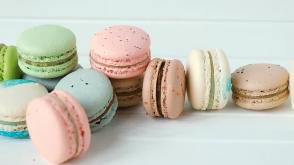 Multicolored Macaroons or Macarons Lie on a White Wooden Background, a Row of Almond Cookies