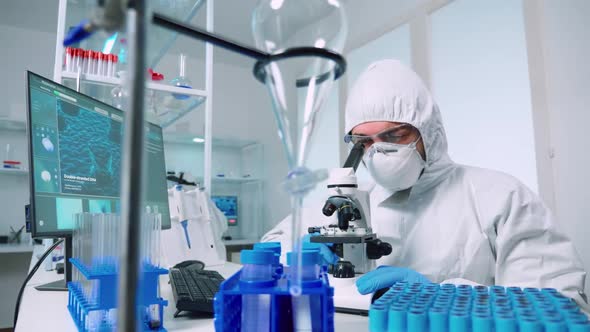 Research Scientist in Coverall Looking at Samples Under Microscope