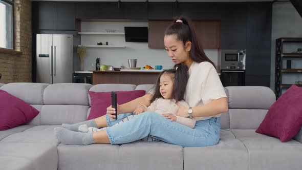 Lovely Mother and Child Using Smartphone on Couch