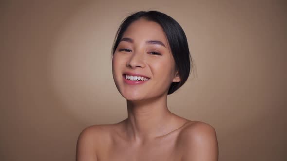 Beautiful Sensitive Young Asian Woman Smiling and Touching Bare Shoulders