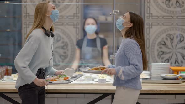 Cheerful Female Friends Taking Trays with Food in Selfservice Restaurant and Walking To Camera