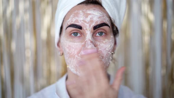 young woman with cosmetic mask on her face and with cosmetic paint on her eyebrows