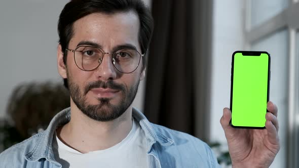 Close-Up Of a man with Glasses Using a Smartphone with a Green screen Online, Standing Near a Window