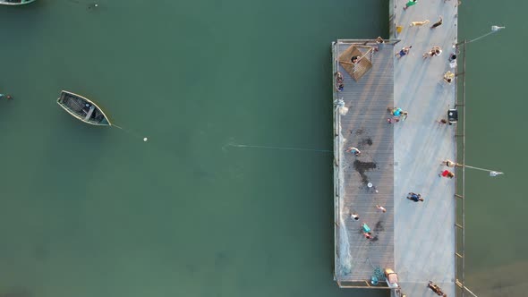 Fisherman Throws Out Fishing Net in the Sea from Pier, Aerial Top Down