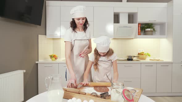 Mother in Kitchen Apron and Hat Teaching Daughter To Cook