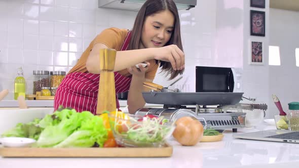 Young Asian woman cooking in kitchen at home. The wife is cooking a special meal for her husband.