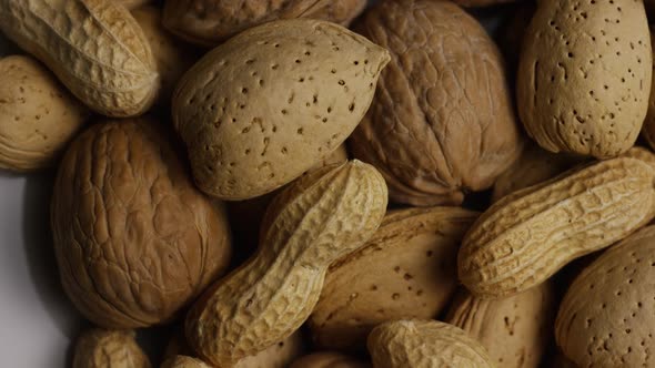 Cinematic, rotating shot of a variety of nuts on a white surface