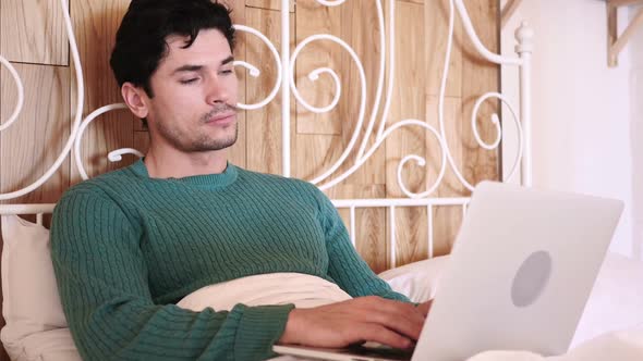 Man Sitting in Bed Working on Laptop
