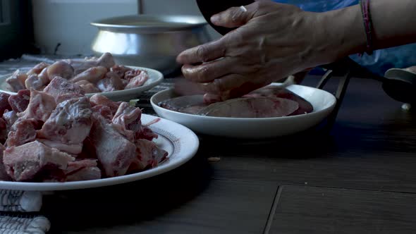 Close Up View Of Raw Meat On Plate On Floor With Hands Of Women Slicing The Raw Fish Small Pieces on