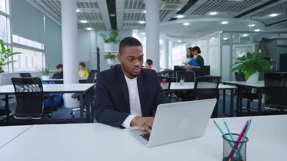 Black Businessman Working on Laptop in Open Space Office