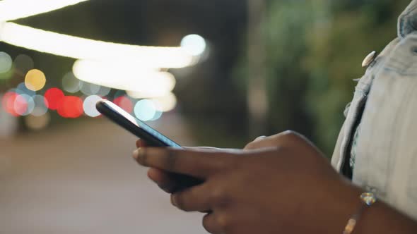 Cheerful African Woman texting on Mobile Phone Outdoors