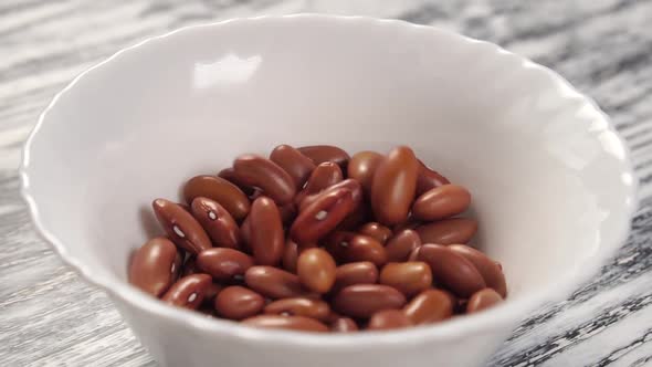 Red Kidney Beans fall and fill a white ceramic plate. 