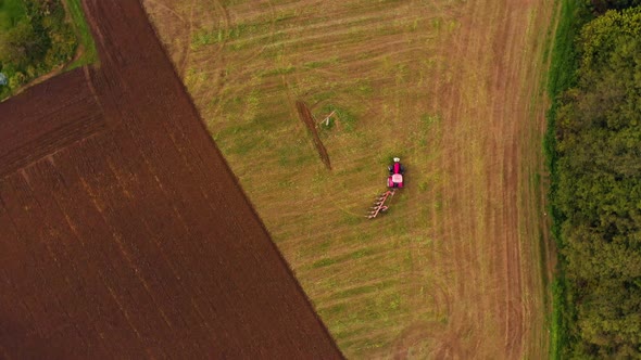 Farmer working od the ffarm field driving red tractor