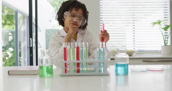 Happy biracial boy making chemistry experiments, holding test tube