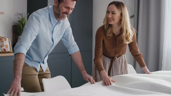 Caucasian couple laying table with a white tablecloth. Shot with RED helium camera in 8K.