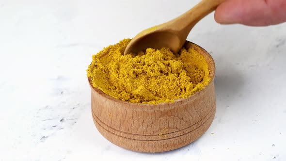 Chef Taking with Wooden Spoon Spices Ground Curry or Turmeric From Wooden Spice Jar