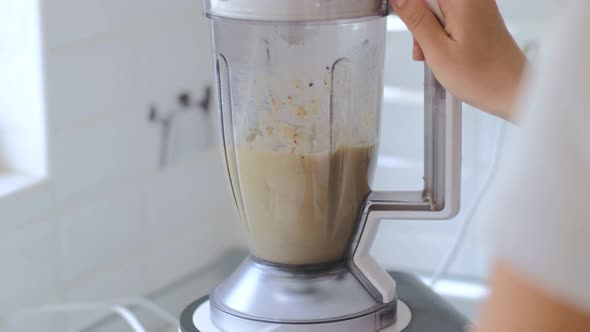 Making fruit smoothies, women's hands with a blender. Healthy diet at home in the kitchen