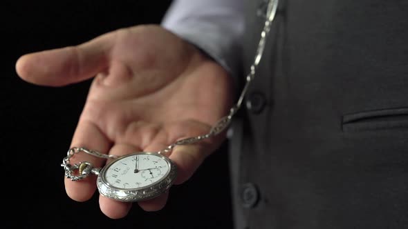 Watchmaker Pulls Out an Antique Watch on a Chain and Puts It in Her Palm. Black Background. Sound
