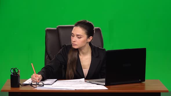 Woman Manager Works on a Laptop and Takes Notes, Green Screen Background,  Slow Motion