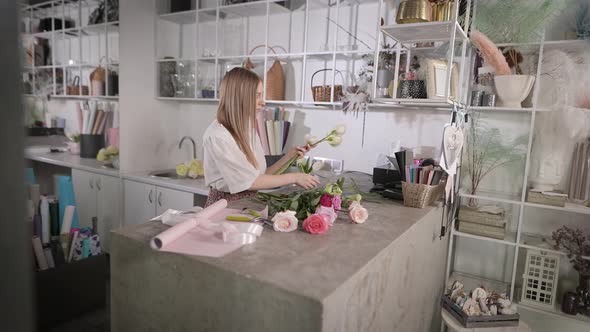 A Woman Florist at the Workplace Collects a Flower Arrangement