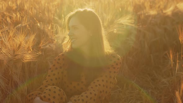 Pregnant woman in the rays of the sunset in the field