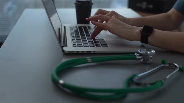 Tracking Shot Closeup of Hands of Unrecognizable Female Practitioner Doctor Using Typing on Laptop