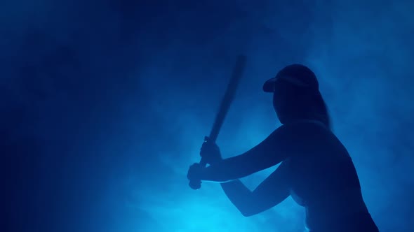 silhouette of baseball player with bat hits ball during game.