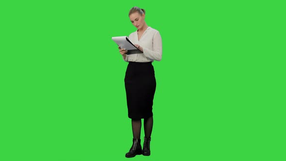 Young Businesswoman Reading Documents Aprroving the Result on a Green Screen, Chroma Key.