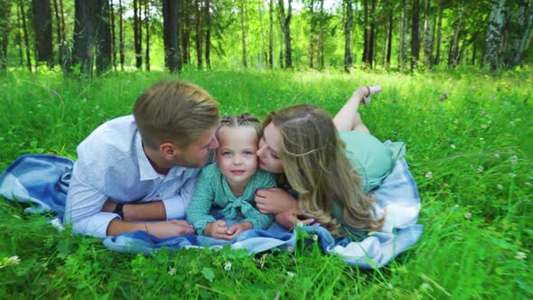 Young Family Lie on the Grass in the Summer Park