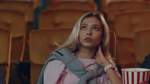 young caucasian woman watching horror movie in cinema theate.