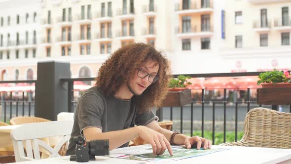 Male Traveler with Curly Hair Holding Map and Search Way