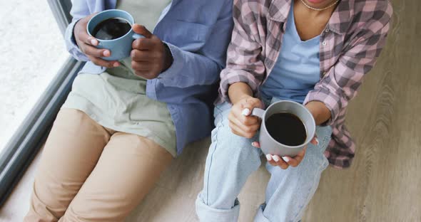 Video of midsection of african american couple drinking coffee and talking at home