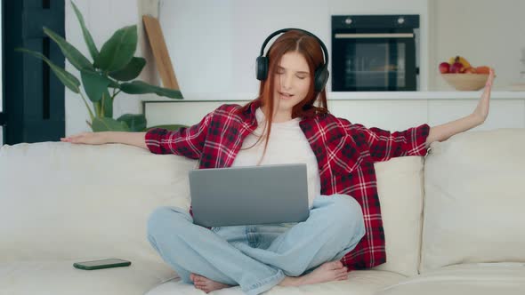 Young Carefree Girl with Laptop in Lotus Pose Listens Loud Favorite Music Enjoys Song Audio Track