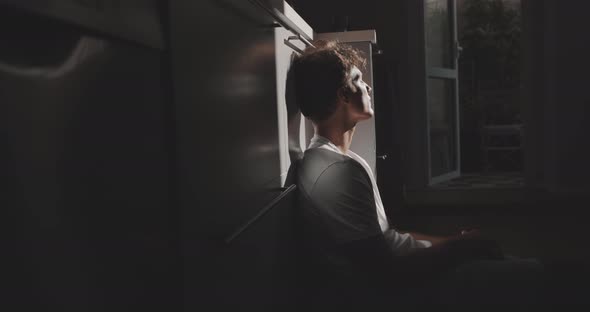 A boy is sitting on the floor appreciating the sunlight that’s coming in from the window