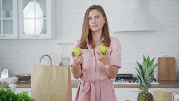 Beautiful woman in light dress holding green apples.