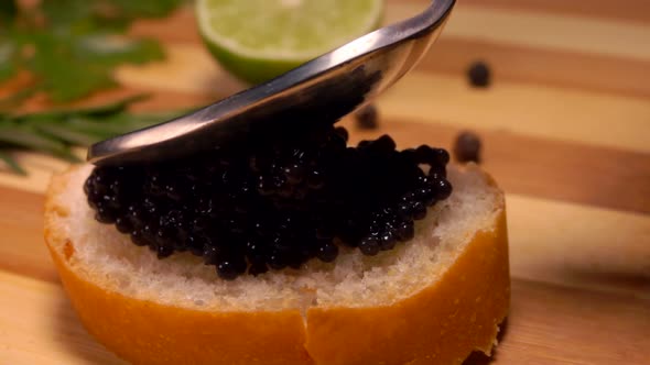 Spoon Smears Black Caviar on White Bread