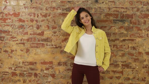 Caucasian woman showing her outfit on a brick wall