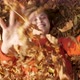  Happy woman playing throws up dry leaves in park - VideoHive Item for Sale