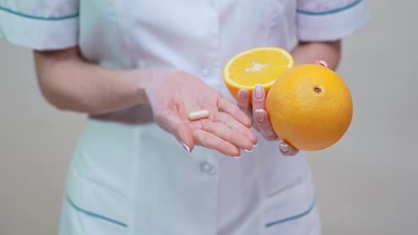 Nutritionist Doctor Healthy Lifestyle Concept - Holding Vitamin Pill and Orange Fruit