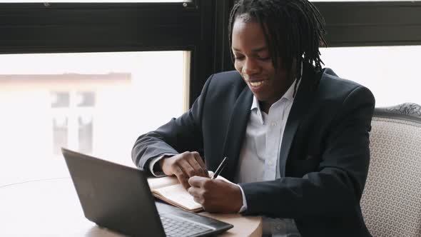 Focused Businessman Worjing at a Cafe with Laptop and Papers