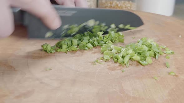 Slider Shot of Chopping Green Onions With a Chef's Knife on a Wooden Cutting Board