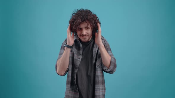 The Young Curlyhaired Hipster Hears News That Shocks Him and Shouts Wow with His Hands on His Head