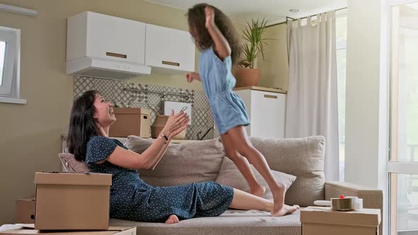 Young Mother and Her Little Daughter Jumping on Bed. Funny Pillow Fight. Play Together and Enjoy the